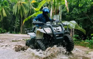 ATV riding through a muddy water crossing during a Cozumel ATV tour in Mexico